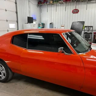 Orange classic coupe with dark tinted side windows.