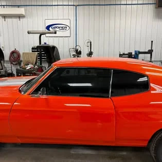 Orange coupe from the side, tinted windows.